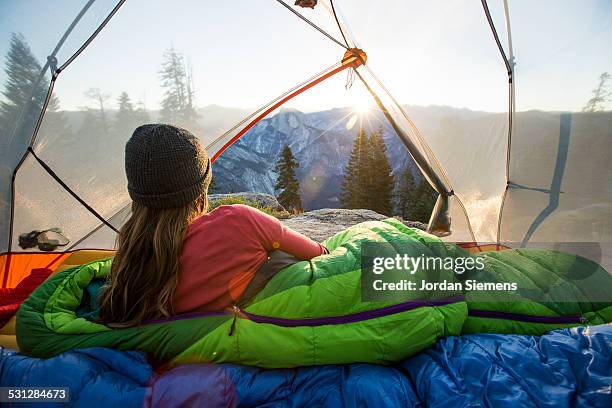 a woman watching sunrise from a tent. - tent foto e immagini stock