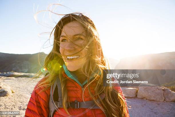 a happy female smiles while hiking. - brown hair blowing stock pictures, royalty-free photos & images