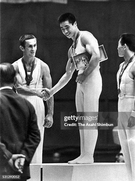 Gold medalist Swao Kato of Japan shakes hands with silver medalist Mikhail Voronin of Soviet Union while bronze medalist Akinori Nakayama of Japan...