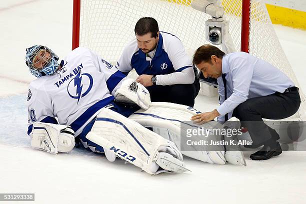 Ben Bishop of the Tampa Bay Lightning is looked over by a team physician after a play at the net during the first period against the Pittsburgh...