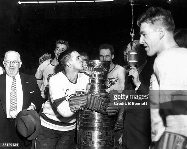 Ted Lindsay of the Detroit Red Wings kisses the cup as manager Jack Adams and the rest of the Wings celebrate winning the Stanley Cup after beating...