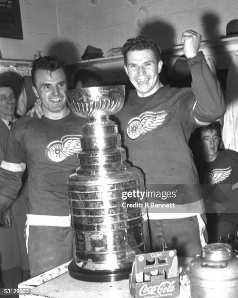 Pete Babando and goalie Harry Lumley of the Detroit Red Wings celebrate in the locker room with the Stanley Cup after defeating the New York Rangers...