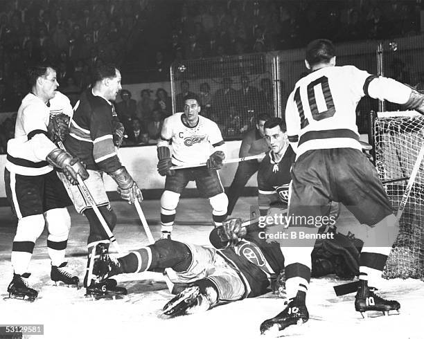 Bud MacPherson of the Montreal Canadiens goes to the ice as goalie Gerry McNeil braces himself for a save against Metro Prystai and Gordie Howe of...