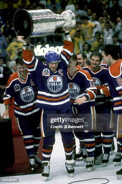 Mark Messier of the Edmonton Oilers hoists the Stanley Cup over his head as his teammates celebrate their Game 5 win over the Boston Bruins on May...
