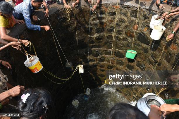 Indian villagers throw containers attached to ropes into a well to collect their daily supply of potable water after a tanker made its daily delivery...