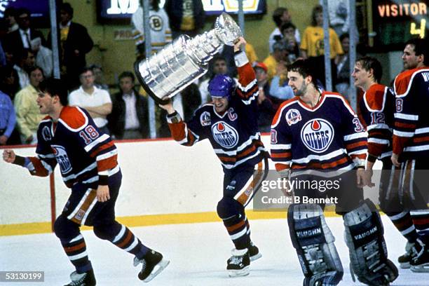 Mark Messier of the Edmonton Oilers hoists the Stanley Cup over his head as he and teammates Craig Simpson and goalie Bill Ranford celebrate their...