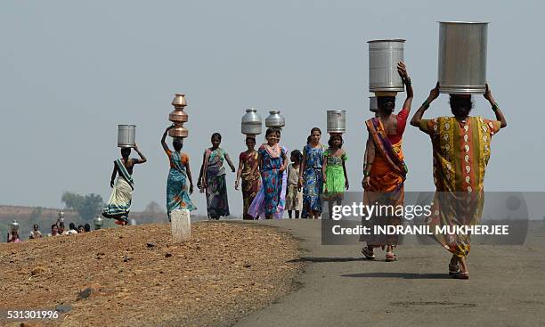 Indian villagers carry containers home after collecting supplies of potable water from a well following a tanker's daily delivery in Shahapur, some...