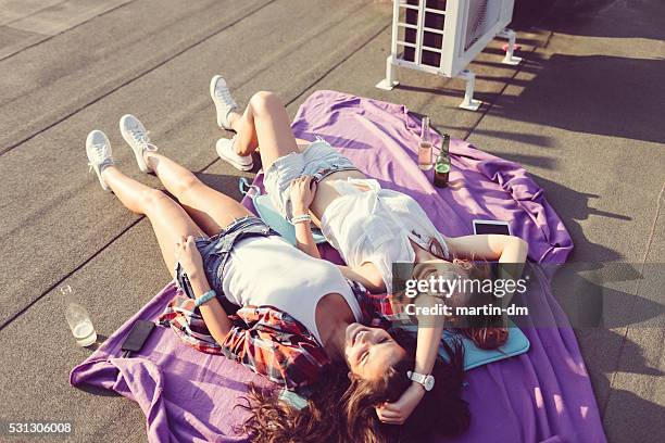 mädchen lachen und sonnenbaden auf dem dach - girls sunbathing stock-fotos und bilder
