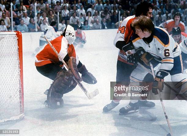 Goalie Bernie Parent of the Philadelphia Flyers waits for the shot as teammate Joe Watson defends against Jim Schoenfeld of the Buffalo Sabres during...