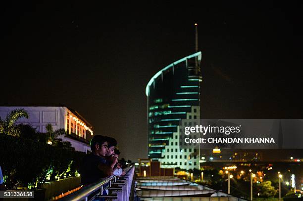 In this photograph taken on May 11 Indian people look over a mall in the DLF Cyber City area of Gurgaon, 32 kilometres southwest of the capital New...