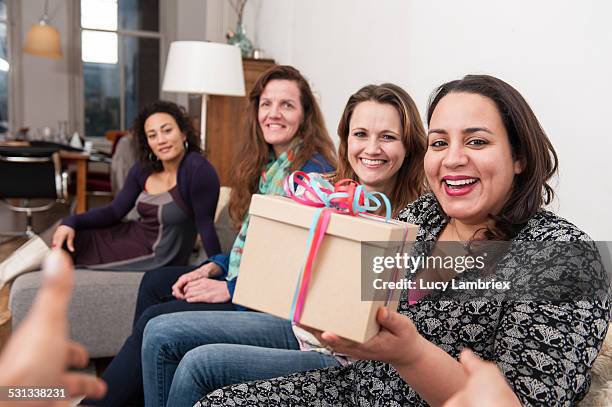 smiling women handing birthday gift to the viewer - 40 birthday stock pictures, royalty-free photos & images