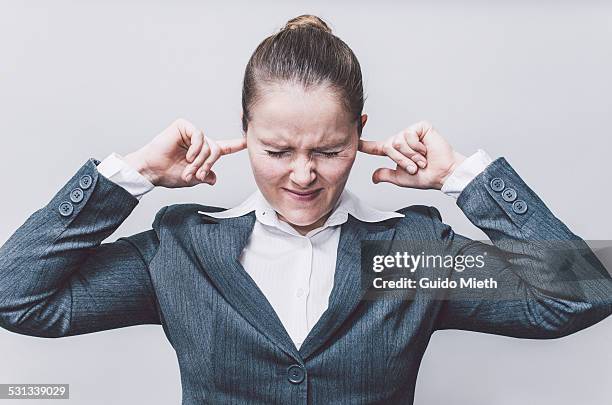 businesswoman with finger in ears. - covering ears stock-fotos und bilder