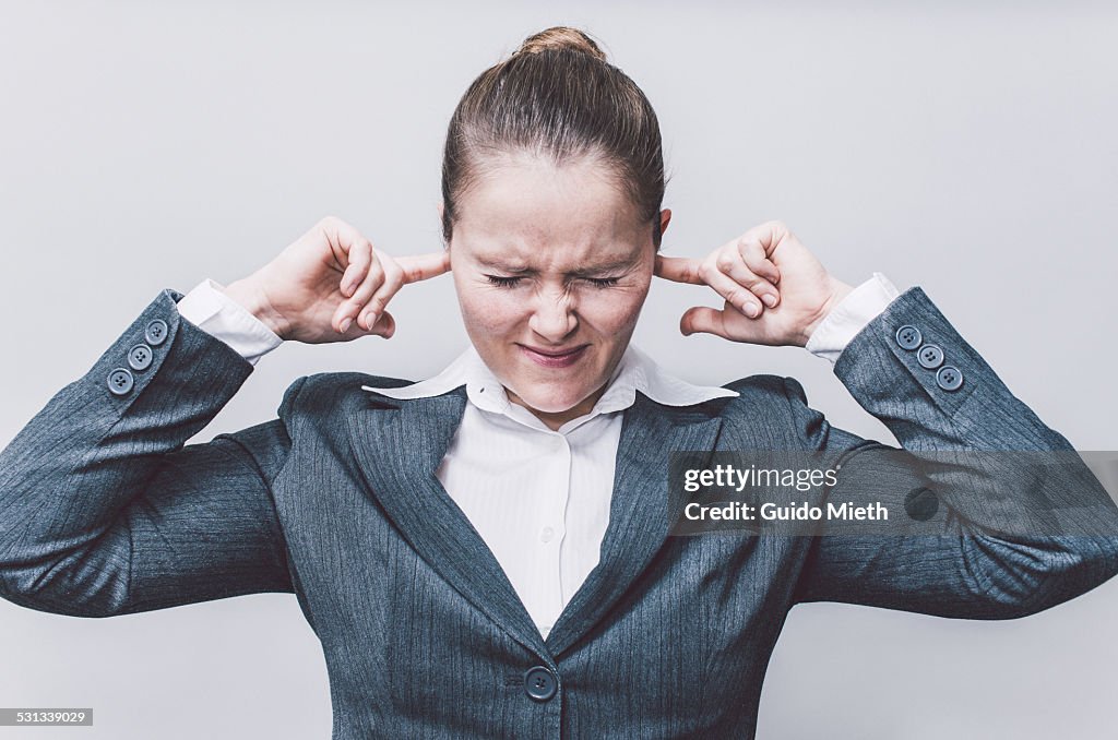 Businesswoman with finger in ears.