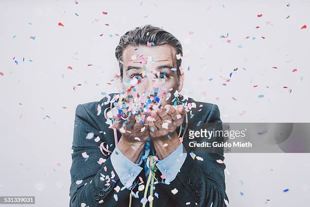 business man blowing confetti. - celebration stock-fotos und bilder