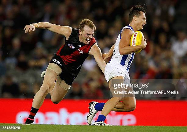 Ben Jacobs of the Kangaroos is tackled by Brendon Goddard of the Bombers during the 2016 AFL Round 08 match between the Essendon Bombers and the...