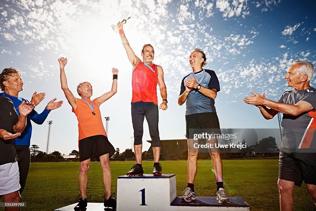 Three mature athletes on podium with medals