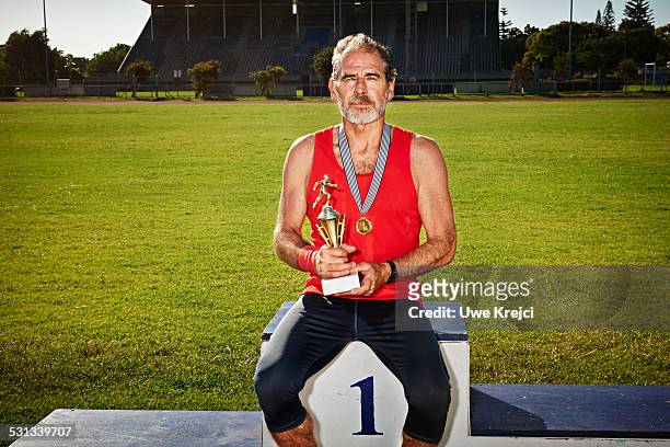 senior male athlete holding a trophy - sportsperson medal stock pictures, royalty-free photos & images