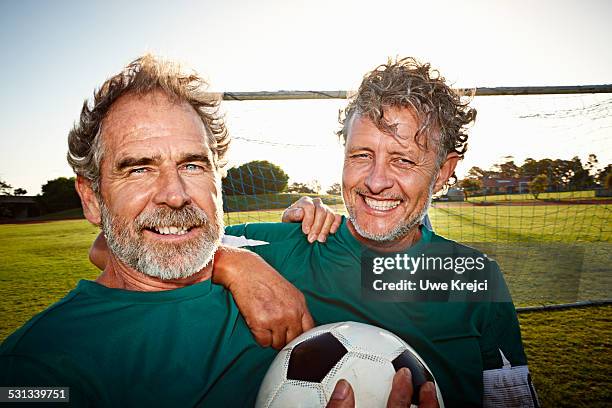 portrait of two mature soccer players smiling - two guys playing soccer stockfoto's en -beelden