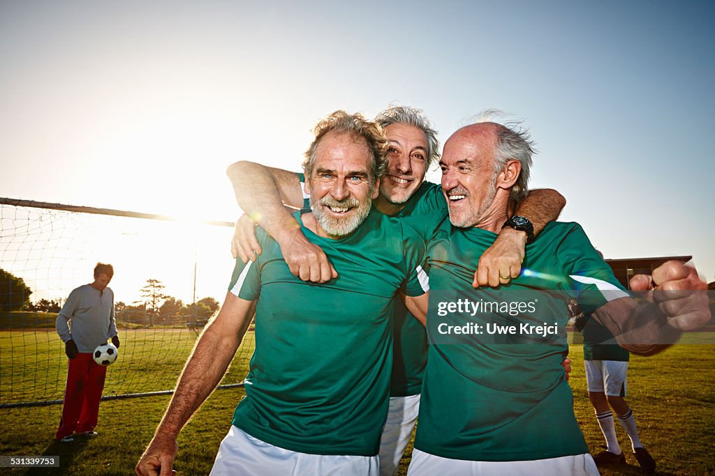 Three senior male soccer players celebrating