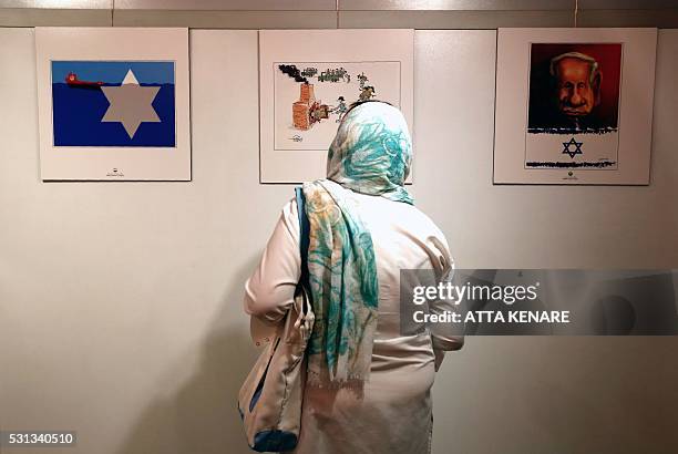 An Iranian woman looks at anti-Israel cartoons displayed at the second international exhibition of drawing and cartoons on the Holocaust in Tehran on...