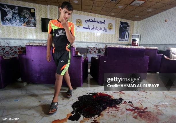 An Iraqi boy walks past the blood stains and debris at a cafe, that was popular with local fans of Spain's Real Madrid football club, in the Balad...