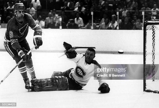 Goalie Gump Worsley of the Montreal Canadiens reaches to stop the puck from entering the net shot by Frank St. Marseille of the St. Louis Blues...
