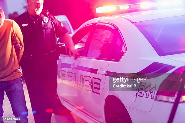 polizist fesselnde ein junger mann bei nacht - police lights stock-fotos und bilder