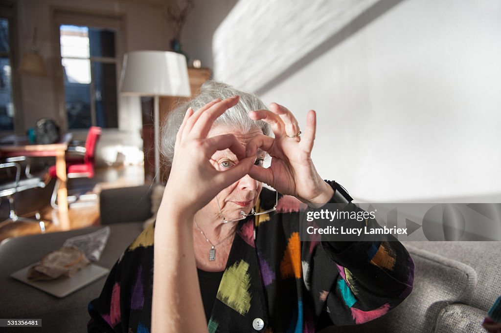 Senior woman making glasses with hands