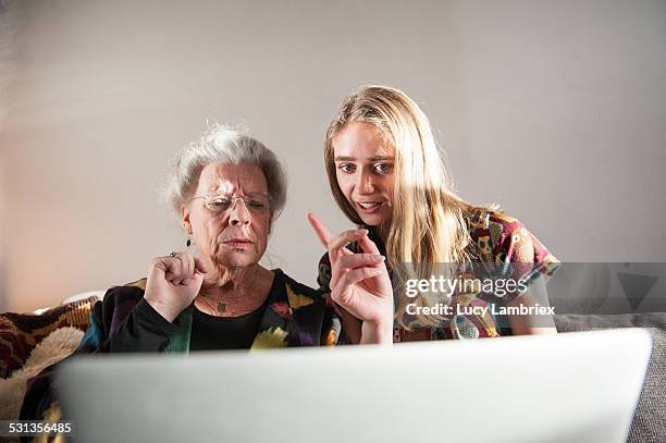 young woman showing senior lady how to work laptop - old technology vs new technology stock pictures, royalty-free photos & images