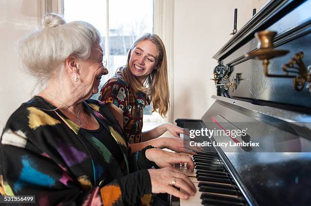 grandmother and granddaughter playing the piano - playing music together stock-fotos und bilder