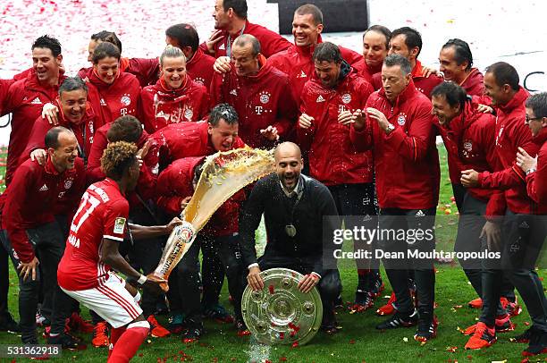 Head coach Josep Guardiola of Bayern Muenchen is poured beer by David Alaba while celebrating Bundesliga champions with staffs after the Bundesliga...