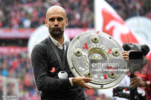 Head coach Josep Guardiola of Bayern Muenchen poses with the Meisterschale as he celebrates the Bundesliga champions after the Bundesliga match...
