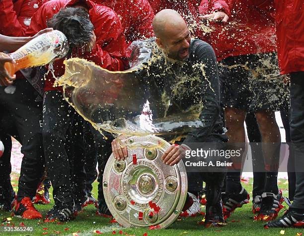 Team coach Josep Guardiola of Bayern Muenchen receives a beer shower from David Alaba during the German Championship celebration after the Bundesliga...