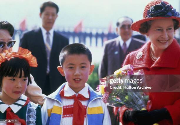 Queen Elizabeth II with school children during a tour of China, October 1986.