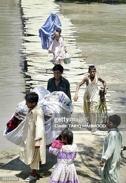 An Afghan refugee family leaves their flood affected camp in Khazana village, some 30 kilometers from Peshawar, 23 June 2005. Hundreds of villagers...