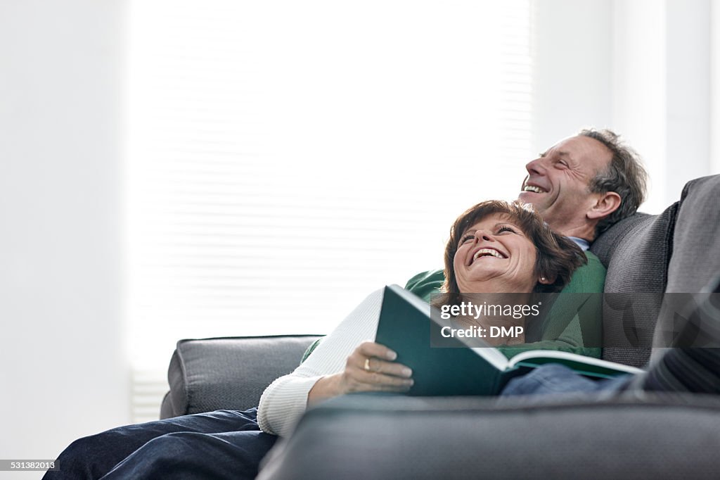 Älteres Paar entspannenden auf sofa mit einem Buch