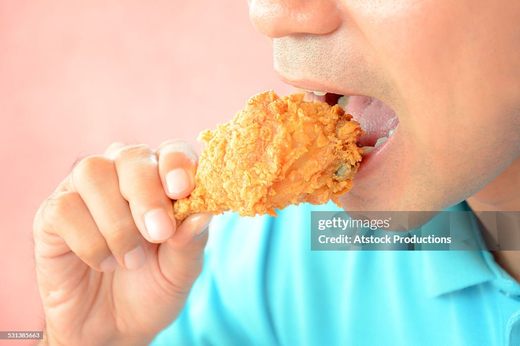 Man eating fried chicken leg or drumstick