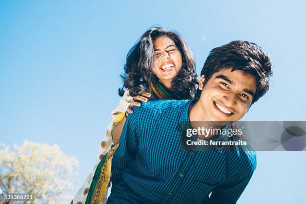 young indian couple piggyback - indian subcontinent ethnicity stockfoto's en -beelden