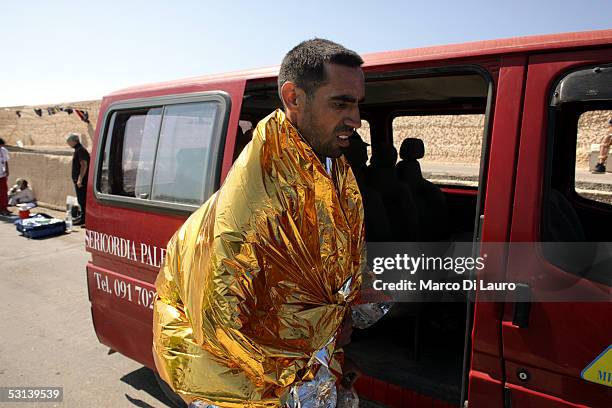 An Illegal immigrant is seen covering himself with a thermal blanket as he waits to be sent to a temporary holding center for foreign nationals on...