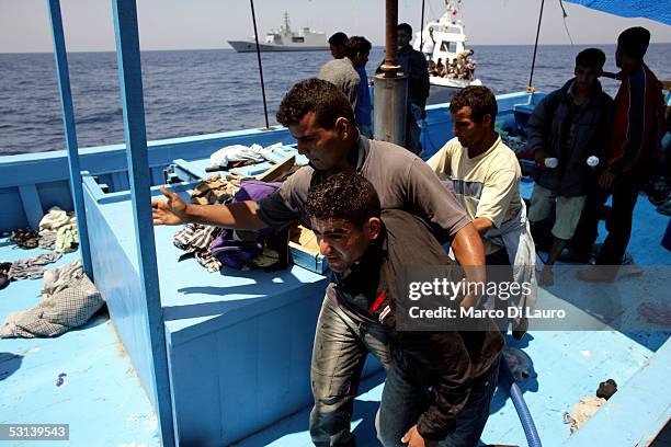 An exhausted Illegal immigrant is taken by a fellow on board of a boat of Italian Custom Police "Guardia di Finanza" on June 21, 2005 in Lampedusa,...