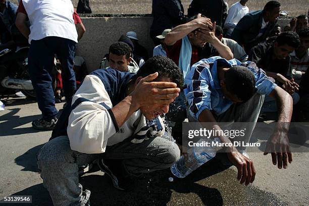 Illegal immigrants wash their faces as they wait to be sent to a temporary holding center for foreign nationals on June 21, 2005 in Lampedusa, Italy....