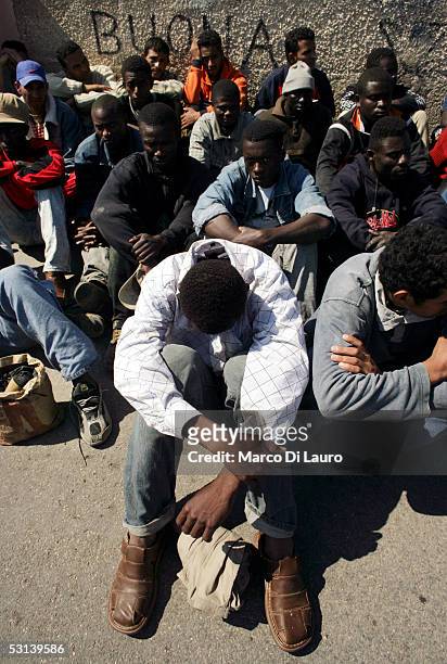 Illegal immigrants wait to be sent to a temporary holding center for foreign nationals on June 21, 2005 in Lampedusa, Italy. Tens of thousands of...