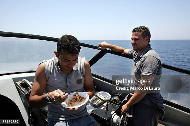 An Italian custom Police "Guardia di Finanza" Officer eat a plate of pasta as his unit approach a boat loads with illegal Immigrants on June 21, 2005...