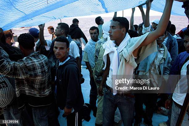 Illegal immigrants wait to be taken on board by a boat of Italian Custom Police "Guardia di Finanza" on June 21, 2005 in Lampedusa, Italy. Tens of...