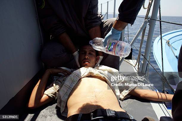 Italian custom Police "Guardia di Finanza" Officers give water to an unconcious illegal Immigrant after they took him on board on June 21, 2005 in...