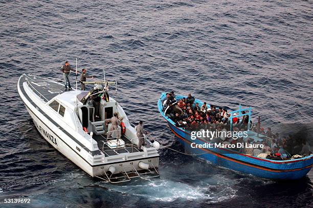 An Italian Custom Police "Guardia di Finanza" boat approaches a boat loaded with illegal immigrants on June 21, 2005 in Lampedusa, Italy. Tens of...