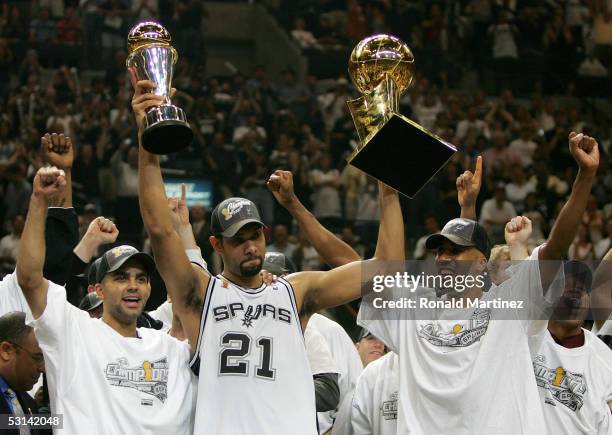 Tim Duncan, center, holds up the Finals MVP trophy and the Larry O'Brien trophy as teammates Tony Parker, left, and Bruce Bowen of the San Antonio...