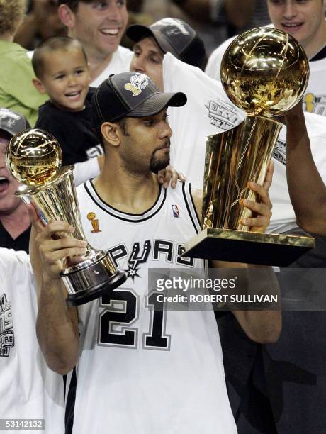 Tim Duncan of the San Antonio Spurs looks at the championship trophy while holding his MVP trophy after his team's victory over the Detroit Pistons...
