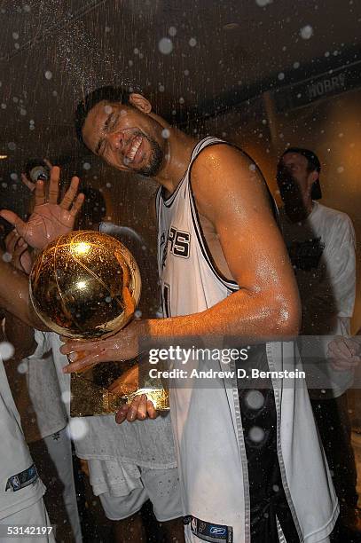 Finals MVP Tim Duncan of the San Antonio Spurs celebrates with Larry O'Brien trophy in the locker room as he is sprayed with champagne following the...