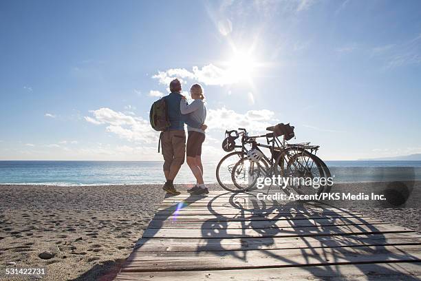 bicycling couple look out to sea from beach wharf - look back 個照片及圖片檔